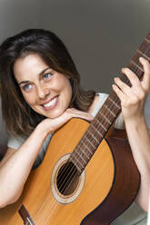 Lächelnde Frau mit Gitarre im Schlafzimmer - AFVF06874