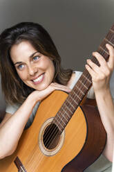 Smiling woman with guitar in bedroom - AFVF06874