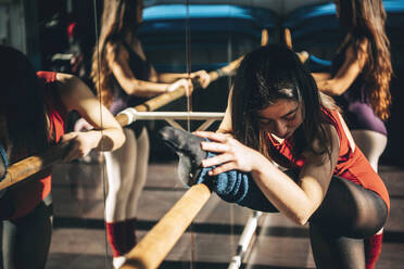 Konzentrierte Balletttänzerinnen trainieren an der Stange vor dem Spiegel im Studio. - ADSF07182