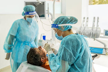 Doctor and nurse with male patient in dentist's clinic - DLTSF00932