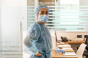 Female dentist looking away while standing in office - DLTSF00942