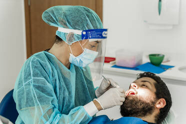 Eine Krankenschwester untersucht einen männlichen Patienten in einer Zahnklinik - DLTSF00949