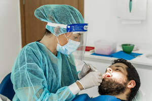 Female nurse examining male patient in dentist's clinic - DLTSF00949