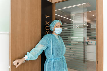 Zahnärztin in Schutzkleidung an der Tür stehend - DLTSF00952
