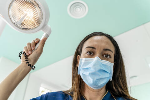 Doctor with adjustable light working in dentist's clinic stock photo