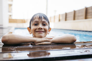 Smiling boy leaning on poolside - JRFF04685