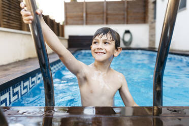 Lächelnder Junge hält Leiter im Schwimmbad - JRFF04691