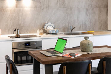 Laptop und Smartphone auf dem Esstisch in der modernen Küche zu Hause - EIF00141