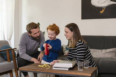 Süßer Junge zeigt Spielzeugroboter lächelnden Eltern im Wohnzimmer zu Hause - EIF00154
