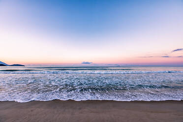 Sonnenuntergang am Strand mit kleinen Wellen, die sich in der Nähe brechen - CAVF87688