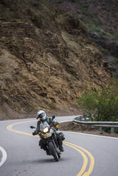 Woman on touring motorbike riding twisting road in Argentina - CAVF87753