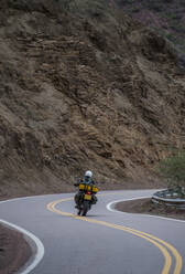 Woman on touring motorbike riding twisting road in Argentina - CAVF87754