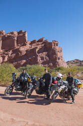 Gruppe von Freunden steht neben Reisemotorrädern in der Wüste - CAVF87757