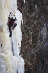 Junger Mann klettert auf gefrorenem Wasserfall in Island - CAVF87780