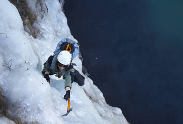 Junger Mann klettert auf gefrorenem Wasserfall in Island - CAVF87781