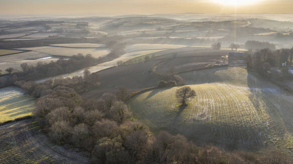 Luftaufnahme per Drohne von frostiger Hügellandschaft in der Morgendämmerung im Frühling, Devon, England, Vereinigtes Königreich, Europa - RHPLF16965