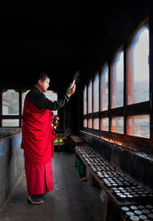 Porträt, Bhutanischer buddhistischer Mönch zündet Kerzen an, damit die Gläubigen beten können, Kloster Tamzhing, Bezirk Bumthang, Bhutan, Asien - RHPLF17029