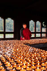 Porträt, Bhutanischer buddhistischer Mönch zündet Kerzen an, damit die Gläubigen beten können, Kloster Tamzhing, Bezirk Bumthang, Bhutan, Asien - RHPLF17030