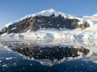 Eisbedeckte Berge spiegeln sich im ruhigen Wasser des Neko-Hafens, Antarktis, Polarregionen - RHPLF17035