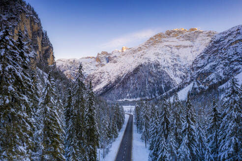 Luftaufnahme per Drohne vom Sonnenaufgang auf der Panoramastraße Toblach-Misurina entlang verschneiter Wälder, Dolomiten, Südtirol, Italien, Europa - RHPLF17058