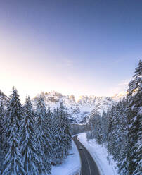 Aerial view by drone of car traveling on the scenic road Dobbiaco-Misurina along snowy woods at dawn, Dolomites, South Tyrol, Italy, Europe - RHPLF17060