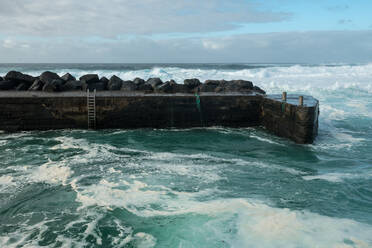 Breathtaking view of amazing stormy sea waving near weathered stony pier on cloudy day - ADSF07296