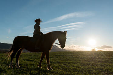 Frau reitet Pferd gegen Sonnenuntergang Himmel auf Ranch - ADSF07301