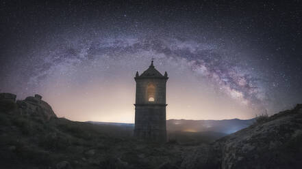 Old fortress building in rocky valley under bright night sky with majestic stars - ADSF07325
