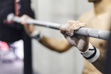 Crop shirtless male lifting barbel wit h weights in gym on blurred background - ADSF07370