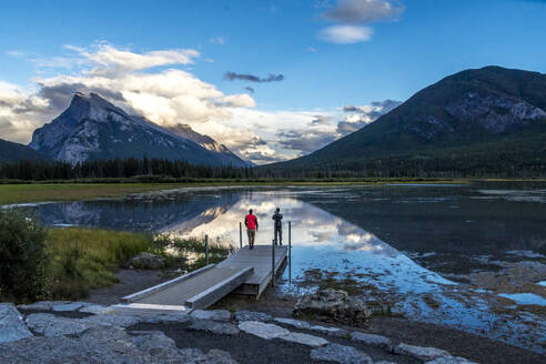 Rückenansicht von Touristen mit Rucksack, die auf einem Steg in Banff, Kanada, stehen - ADSF07413