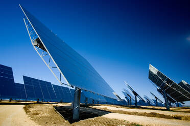 Moderne Solarmodule, die in einem Photovoltaik-Kraftwerk auf einem Feld vor einem wolkenlosen blauen Himmel installiert sind - ADSF07446