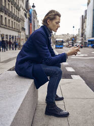Side view of young handsome male in stylish outfit looking at smartphone - ADSF07457