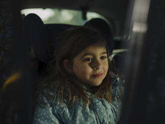 Nahaufnahme eines nachdenklichen Mädchens, das wegschaut, während es im Auto sitzt - GUSF04343