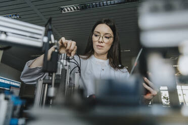 Junge Wissenschaftlerin, die Maschinen im Labor untersucht - MFF05893