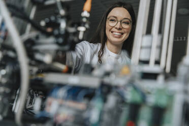 Close-up of smiling female scientist examining machinery in laboratory at factory - MFF05909