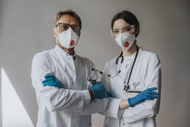 Ärzte mit Masken und verschränkten Armen stehen an einer Wand im Krankenhaus - MFF05943