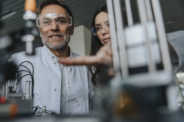 Nahaufnahme von Wissenschaftlern mit Schutzbrillen, die eine Maschine im Labor untersuchen - MFF05947