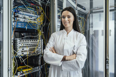 Young woman with arms crossed standing in data center - MFF05958