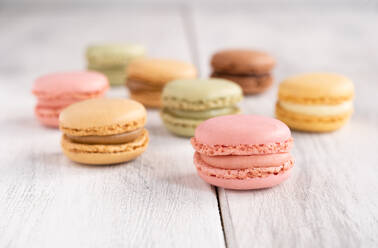 Colorful tasty macaroons stacked in pile against wooden white surface - ADSF07805