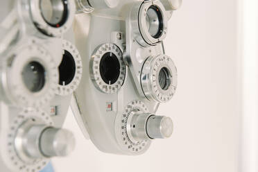 Modern vision test equipment and chair against white wall in optician office in clinic - ADSF08043