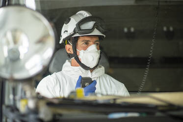 Feuerwehrmann mit Atemschutzmaske und Helm sitzt im Feuerwehrauto und benutzt ein Walkie-Talkie - ADSF08119
