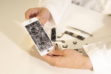 Abgeschnittene Hände mit gebrochenem Smartphone-Display - ADSF08123