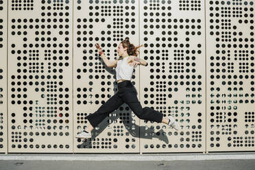 Woman running against wall with holes - MEUF01697