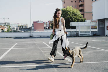 Woman walking with dog in parking lot - MEUF01703