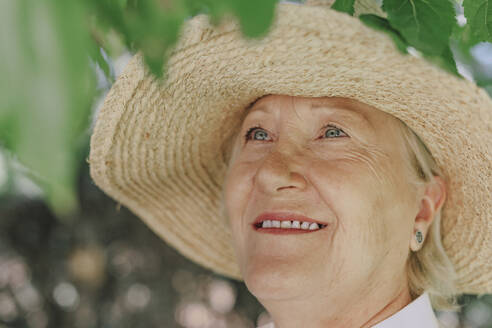 Close-up of smiling senior woman wearing hat looking up - ERRF04117