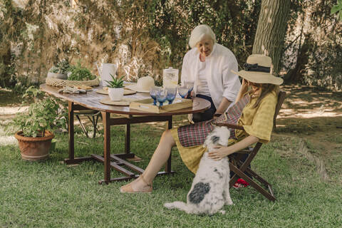 Mother and daughter with dog relaxing in picnic at yard stock photo