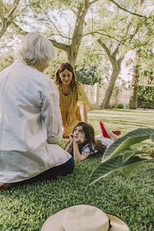 Multi-generation family relaxing on grassy land in yard - ERRF04181