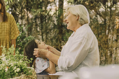 Happy senior woman playing with cute granddaughter in yard - ERRF04189