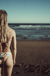Young girl wearing bikini, standing at the beach, Stock Photo