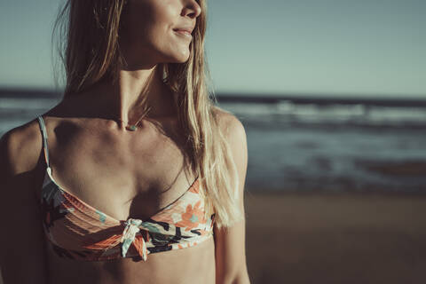 Close-up of young woman wearing bikini standing against sea during sunset stock photo